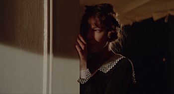 Movie still from “Death on the Nile” (1978), directed by John Guillermin – A young woman standing next to a wall with her hand to her face; Close Up shot, Over the shoulder angle