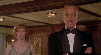 Movie still from “Death on the Nile” (1978), directed by John Guillermin – A man in a tuxedo standing next to a woman in an evening dress; Close Up shot, Low angle