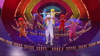 Movie still from “Death to Smoochy” (2002), directed by Danny DeVito – A group of people dressed in clown costumes on a stage; Extreme Wide shot, High angle