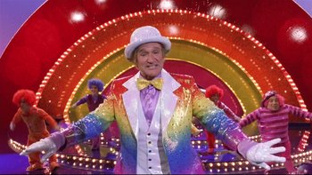 Movie still from “Death to Smoochy” (2002), directed by Danny DeVito – A man wearing a rainbow suit and a hat; Wide shot, Low angle