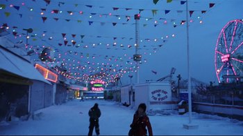 Movie still from “Death to Smoochy” (2002), directed by Danny DeVito – Two people are walking in the snow under lights; Extreme Wide shot, High angle