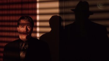 Movie still from “Death to Smoochy” (2002), directed by Danny DeVito – A man standing in front of a window with blinds; Medium shot, Over the shoulder angle