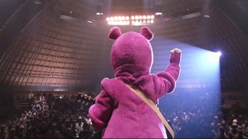 Movie still from “Death to Smoochy” (2002), directed by Danny DeVito – A person dressed in a purple bear costume in front of an audience; Medium shot, Low angle