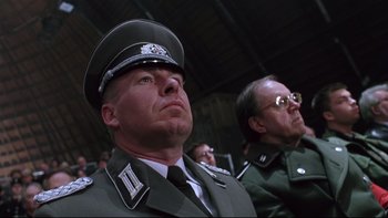 Movie still from “Death to Smoochy” (2002), directed by Danny DeVito – Two men in uniforms are sitting in front of each other; Close Up shot, Low angle