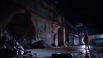 Movie still from “Death to Smoochy” (2002), directed by Danny DeVito – A person standing in front of a building at night; Extreme Wide shot, Low angle