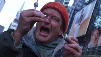 Movie still from “Death to Smoochy” (2002), directed by Danny DeVito – A man in a red hat is holding a piece of food in his hand; Extreme Close Up shot, Low angle