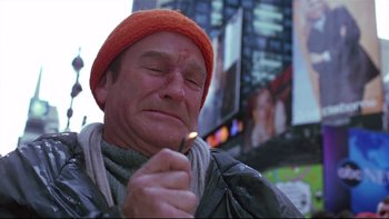 Movie still from “Death to Smoochy” (2002), directed by Danny DeVito – A man in a red hat is lighting a cigarette; Close Up shot, Low angle