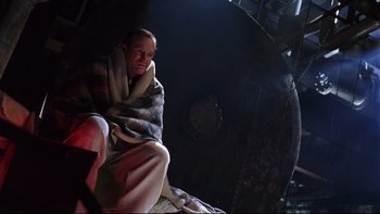Movie still from “Death to Smoochy” (2002), directed by Danny DeVito – A man wrapped in a blanket sitting on a chair; Medium shot, Low angle