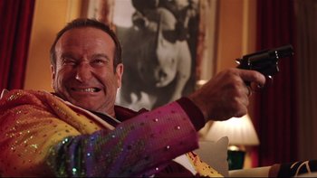 Movie still from “Death to Smoochy” (2002), directed by Danny DeVito – A man wearing a colorful jacket and holding a gun; Close Up shot, Low angle