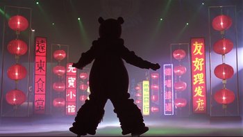Movie still from “Death to Smoochy” (2002), directed by Danny DeVito – A person in a bear costume on a stage; Wide shot, Low angle