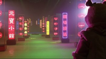 Movie still from “Death to Smoochy” (2002), directed by Danny DeVito – A teddy bear sitting in front of a row of neon signs; Extreme Wide shot, Low angle