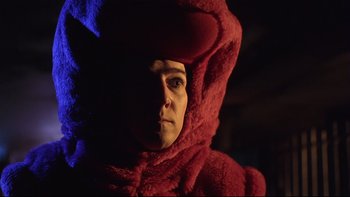 Movie still from “Death to Smoochy” (2002), directed by Danny DeVito – A person wearing a red hooded robe in a dark room; Close Up shot, Low angle