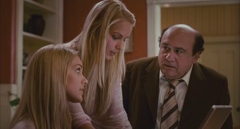 Movie still from “Deck the Halls” (2006), directed by John Whitesell – Two girls and an older man looking at something on a table; Medium shot, Over the shoulder angle