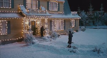 Movie still from “Deck the Halls” (2006), directed by John Whitesell – A woman standing outside of a house in the snow at night; Extreme Wide shot, Low angle