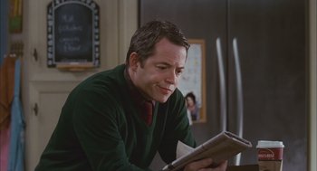 Movie still from “Deck the Halls” (2006), directed by John Whitesell – A man sitting at a table reading a newspaper; Medium shot, Over the shoulder angle