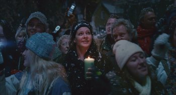 Movie still from “Deck the Halls” (2006), directed by John Whitesell – A woman holding a lit candle in a crowd of people; Medium shot, Over the shoulder angle