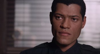 Movie still from “Deep Cover” (1992), directed by Bill Duke – A person wearing a police uniform; Close Up shot, Over the shoulder angle