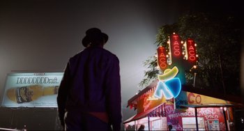 Movie still from “Deep Cover” (1992), directed by Bill Duke – A man standing in front of a neon sign at night; Wide shot, Low angle