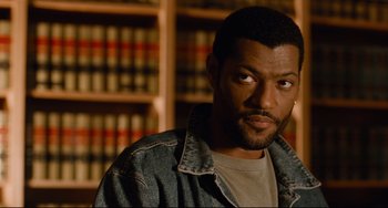 Movie still from “Deep Cover” (1992), directed by Bill Duke – A man in a denim jacket in front of a book shelf; Close Up shot, High angle