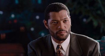 Movie still from “Deep Cover” (1992), directed by Bill Duke – A person wearing a suit and tie; Close Up shot, Over the shoulder angle