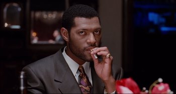 Movie still from “Deep Cover” (1992), directed by Bill Duke – A man in a suit and tie eating a piece of food; Close Up shot, High angle