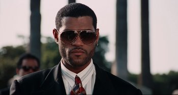 Movie still from “Deep Cover” (1992), directed by Bill Duke – A person wearing a suit and sunglasses; Close Up shot, Low angle