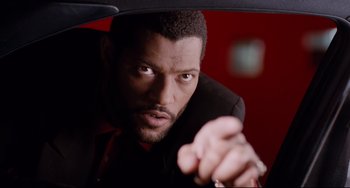 Movie still from “Deep Cover” (1992), directed by Bill Duke – A man in a black suit and red tie looking at the camera; Close Up shot, Over the shoulder angle