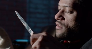 Movie still from “Deep Cover” (1992), directed by Bill Duke – A person holding a knife in his hand; Close Up shot, Low angle