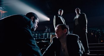 Movie still from “Deep Cover” (1992), directed by Bill Duke – A group of men sitting in front of each other in a dark room; Medium shot, Low angle