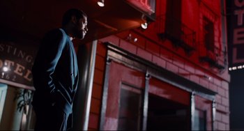 Movie still from “Deep Cover” (1992), directed by Bill Duke – A man standing in front of a red brick building; Medium shot, Low angle