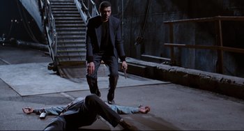 Movie still from “Deep Cover” (1992), directed by Bill Duke – A man standing next to a dead body on the ground; Wide shot, High angle