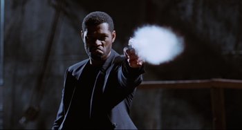 Movie still from “Deep Cover” (1992), directed by Bill Duke – A man in a suit and tie holding a gun; Medium shot, Low angle