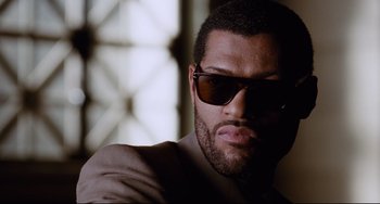 Movie still from “Deep Cover” (1992), directed by Bill Duke – A person wearing a suit and sunglasses; Close Up shot, Low angle