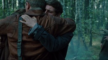 Movie still from “Defiance” (2008), directed by Edward Zwick – Two men hugging each other in the woods; Medium shot, Over the shoulder angle