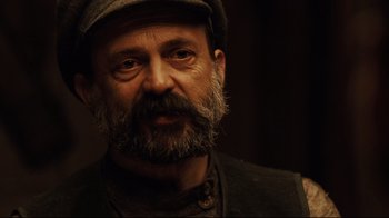 Movie still from “Defiance” (2008), directed by Edward Zwick – A man with a beard wearing a hat and a vest; Close Up shot, Over the shoulder angle