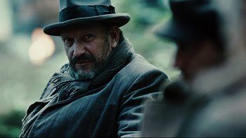 Movie still from “Defiance” (2008), directed by Edward Zwick – A man with a beard wearing a hat and a coat; Close Up shot, Over the shoulder angle