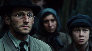 Movie still from “Defiance” (2008), directed by Edward Zwick – A group of people standing next to each other wearing glasses; Close Up shot, Over the shoulder angle