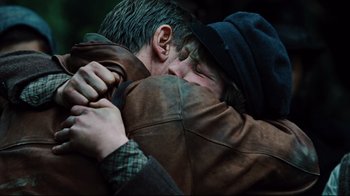 Movie still from “Defiance” (2008), directed by Edward Zwick – Two men are hugging each other in the dark; Close Up shot, Over the shoulder angle
