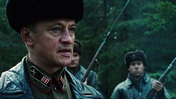 Movie still from “Defiance” (2008), directed by Edward Zwick – A group of men standing next to each other in the woods; Close Up shot, Low angle