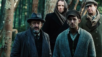 Movie still from “Defiance” (2008), directed by Edward Zwick – A group of men standing next to each other in the woods; Medium shot, Low angle