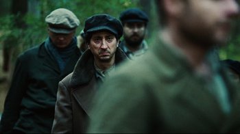 Movie still from “Defiance” (2008), directed by Edward Zwick – A group of men standing next to each other in a forest; Close Up shot, Over the shoulder angle
