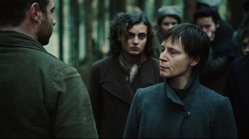 Movie still from “Defiance” (2008), directed by Edward Zwick – A group of people walking through a forest; Close Up shot, Over the shoulder angle