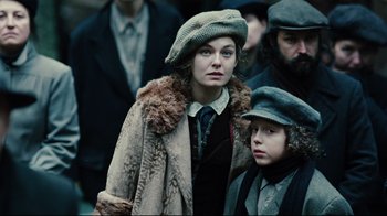Movie still from “Defiance” (2008), directed by Edward Zwick – A woman and a boy are standing in a crowd of people; Medium shot, Low angle