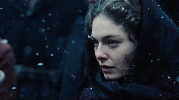 Movie still from “Defiance” (2008), directed by Edward Zwick – A young woman is looking out of a window in the snow; Close Up shot, Low angle