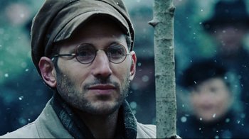 Movie still from “Defiance” (2008), directed by Edward Zwick – A person wearing glasses and a hat; Close Up shot, Over the shoulder angle