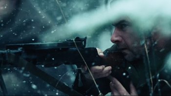Movie still from “Defiance” (2008), directed by Edward Zwick – A man is holding a rifle in the snow; Close Up shot, Over the shoulder angle