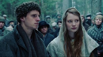 Movie still from “Defiance” (2008), directed by Edward Zwick – A man and a woman standing next to each other in a crowd; Close Up shot, Low angle