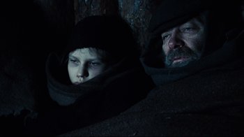 Movie still from “Defiance” (2008), directed by Edward Zwick – A man and a boy in a dark room; Close Up shot, Low angle