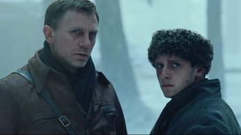 Movie still from “Defiance” (2008), directed by Edward Zwick – Two men standing next to each other in the snow; Medium shot, Low angle