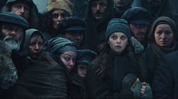 Movie still from “Defiance” (2008), directed by Edward Zwick – A group of people wearing winter clothes and hats; Medium shot, Low angle